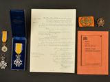 une photo montrant un document, une médaille et d'autres objets posés sur une table