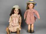 two antique dolls are sitting next to each other on a gray surface