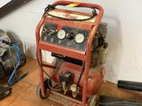 un petit compresseur d'air posé par terre à côté d'autres outils