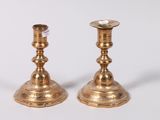 two gold candlesticks sitting on a white surface