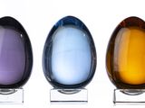 three glass egg shaped vases sitting on a clear stand