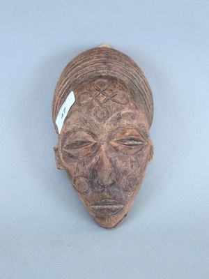 une image représentant un masque en bois sur lequel est accrochée une étiquette au niveau du front