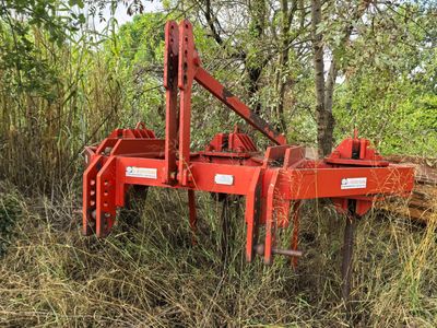 a red plow that is sitting in the grass