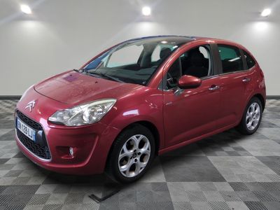 une voiture rouge est garée dans une pièce au sol en damier