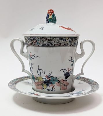 une tasse et une soucoupe posées sur une soucoupe, surmontées d'un oiseau