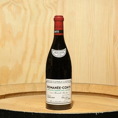 a bottle of wine sitting on top of a barrel