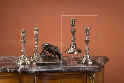 trois bougies posées sur une table en marbre sur laquelle trône une figurine d'oiseau