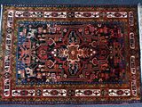 un tapis oriental posé sur une moquette bleue, orné d'un motif rouge et bleu