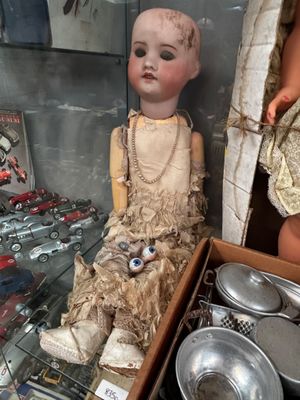 une poupée dans une vitrine, à côté d'autres poupées