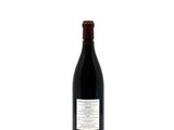 the bottle of wine is sitting on a white surface