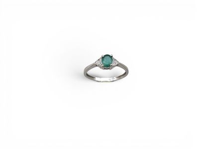 gros plan d'une bague en diamant et émeraude sur fond blanc