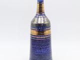 a blue vase with a gold rim on a white background