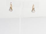 une paire de boucles d'oreilles en or et diamants, présentée sur un présentoir transparent