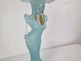 a blue glass vase with a gold earring on it