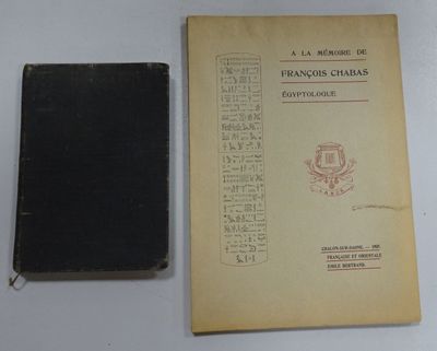 an old book sitting on top of a white table next to a black book