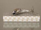 une figurine en argent représentant un poisson, posée sur une boîte