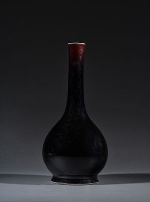un vase noir posé sur une table blanche, près d'un mur noir