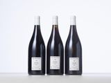 three bottles of wine are lined up on a table