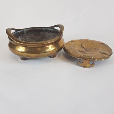deux petits pots en laiton avec leurs couvercles, posés sur une surface blanche