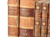 several old books sitting on top of each other on a white surface