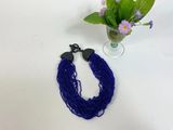 a close up of a blue necklace next to a vase of flowers