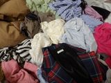 a pile of clothes on a bed with a teddy bear