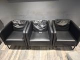 three black leather chairs sitting in a row on the floor