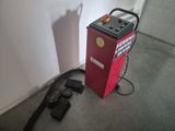a red machine that is sitting on the floor next to a wall
