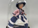 une figurine représentant une femme en robe bleue, placée sous un dôme en verre
