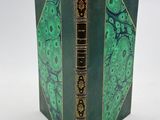 un vieux livre à la couverture verte posé sur une table blanche
