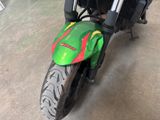 a green motorcycle with a red and yellow stripe parked in a garage