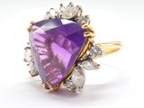 a close up of a ring with a purple stone surrounded by white diamonds