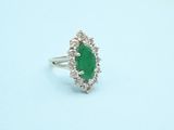 a close up of a ring with a green stone surrounded by diamonds