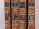 trois vieux livres posés l'un sur l'autre sur une surface blanche