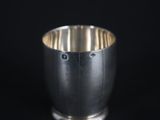 a silver cup that is sitting on a black surface