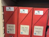 three red binders on a shelf with labels on them