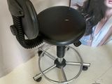 a black stool with a black seat and a magazine on the wall