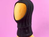 un mannequin en bois coiffé d'un chapeau noir sur fond rose