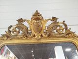 a mirror with a gold frame on the wall in a store