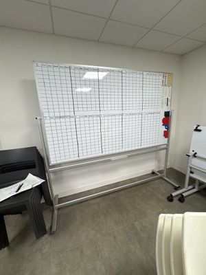 a whiteboard in the corner of a room with a whiteboard on the wall