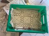 a green plastic box with a crocheted doily on it
