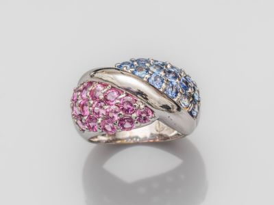 un gros plan d'une bague rose et bleue posée sur une surface blanche