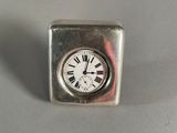 une petite horloge carrée avec des chiffres romains