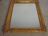 gold framed mirror on the floor with a white wall in the background