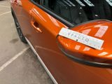 an orange car parked in a parking lot with a sign attached to the side of it