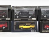 six modèles différents de voitures dans des boîtes, posées sur une surface blanche