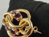a close up of a gold and purple broochle on a pillow