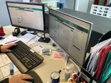 une personne assise à un bureau devant deux écrans d'ordinateur