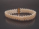 two rows of white pearls with a gold clasp on a black surface