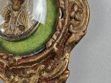 an image of a gold and green pendant with a picture of jesus